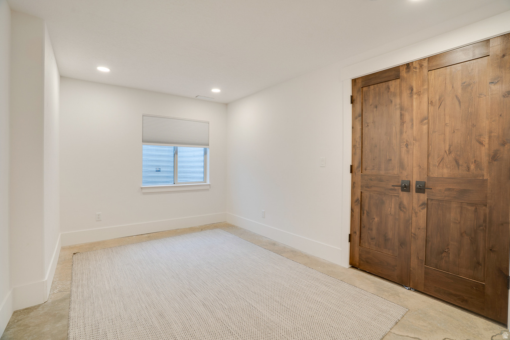 Spacious room featuring rich wood-panel double doors with dark hardware, recessed lighting, and a window with a roller shade
