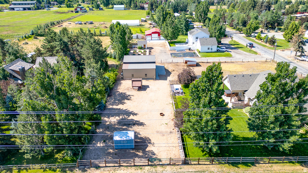 Expansive property featuring a brown barn with a metal roof, a gravel-surfaced area, established trees, and perimeter fencing