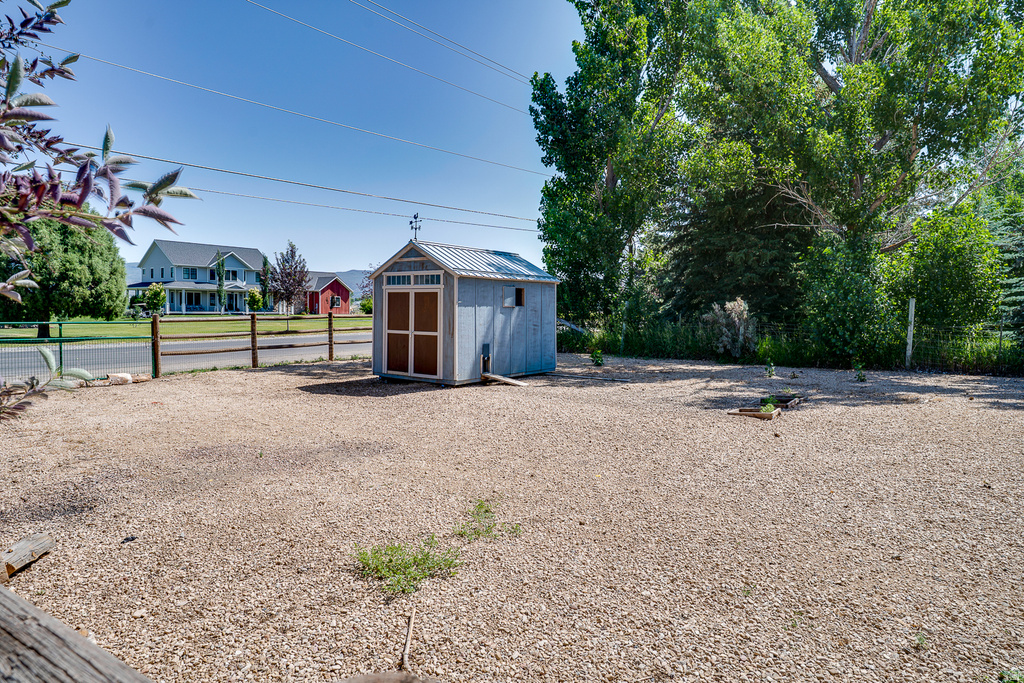 Spacious gravel yard featuring a light blue storage shed with a metal roof and a decorative weathervane