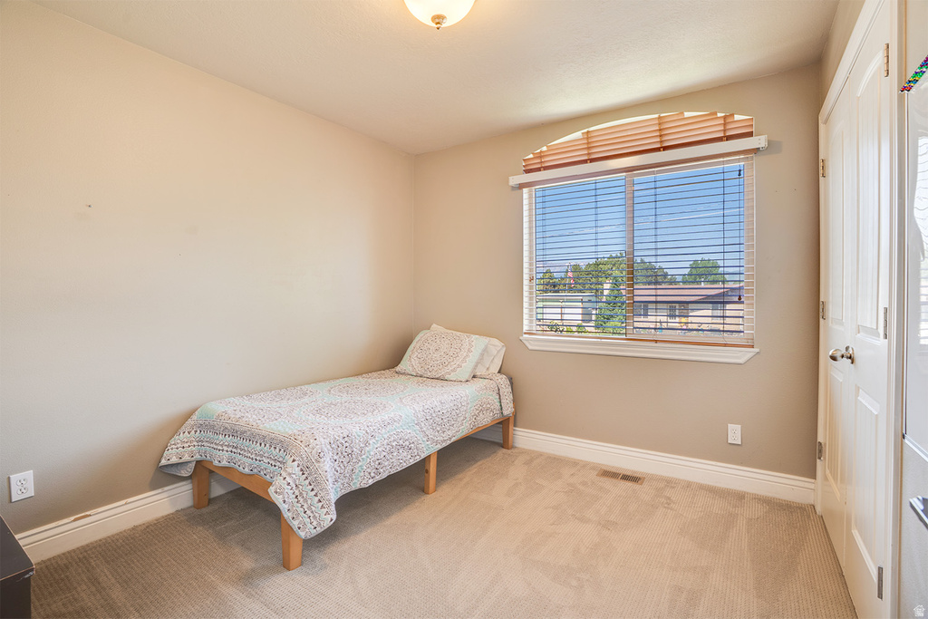Carpeted room with a large arched window featuring horizontal blinds