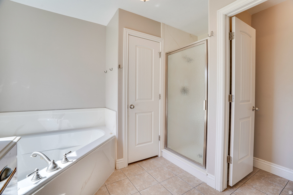 Soaking tub with deck-mounted faucet fixtures and a glass-enclosed shower with a textured privacy panel