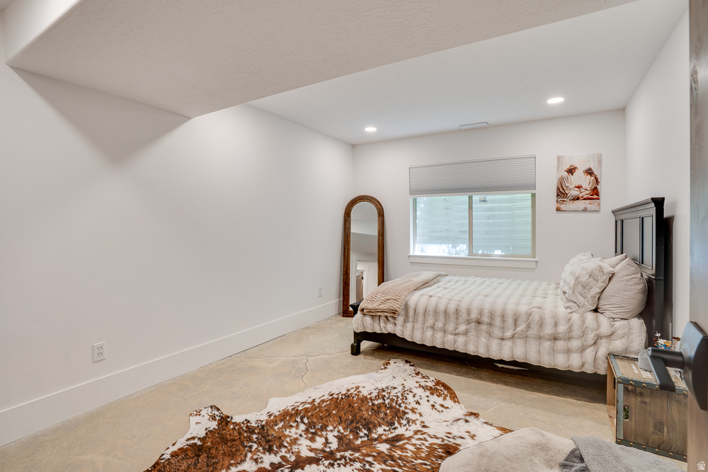 Recessed lighting illuminates this room featuring light-colored flooring, a window with a roller shade, and white walls