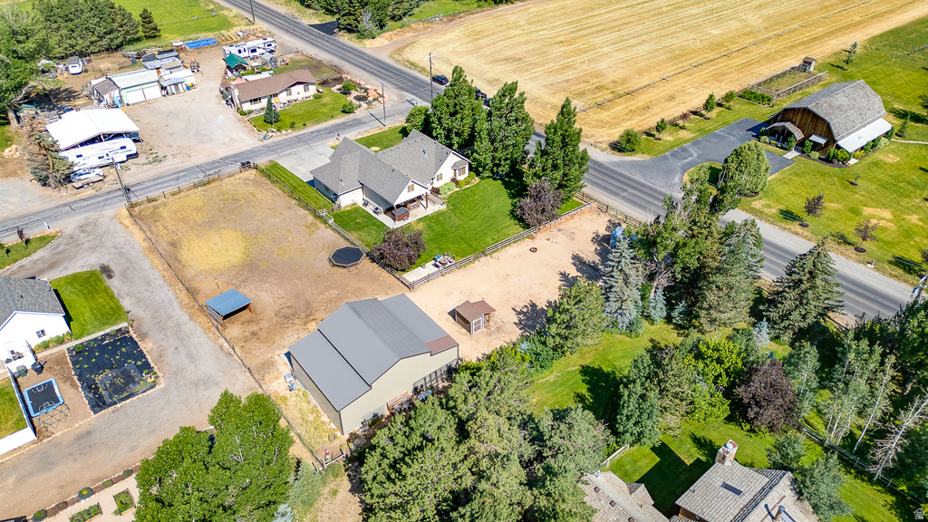Expansive property featuring a main residence with a covered porch, a large detached outbuilding with a gray metal roof, mature trees, and a spacious, fenced lot