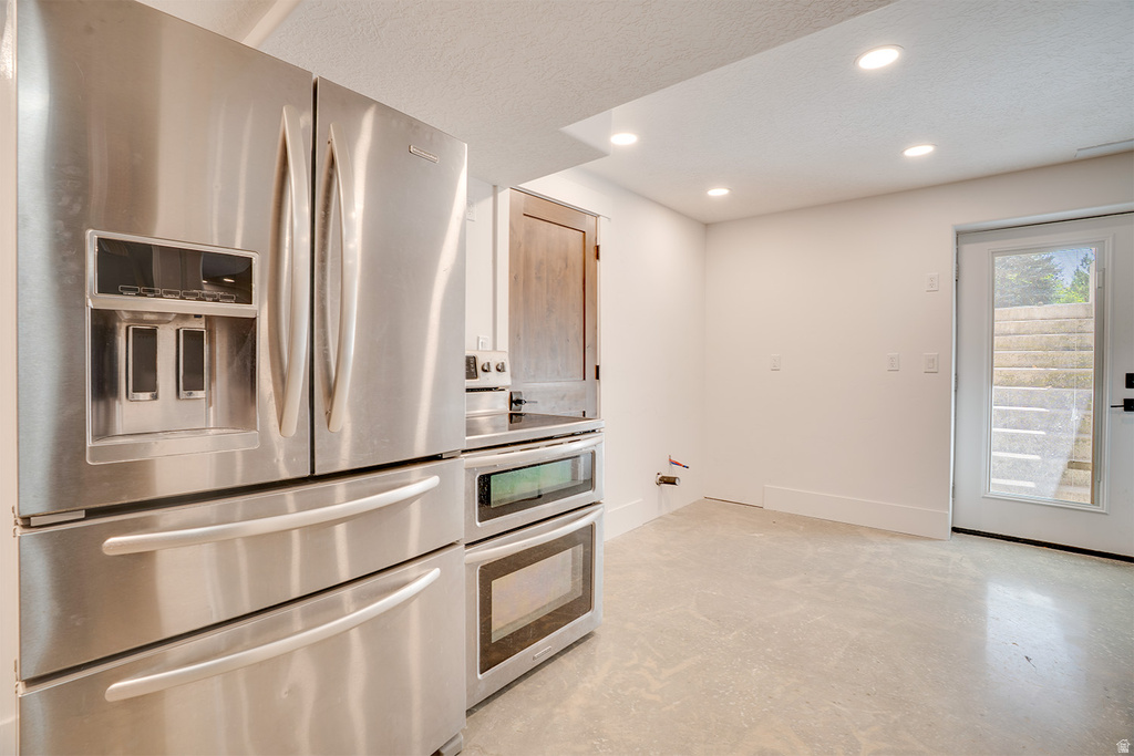 Contemporary kitchen space featuring stainless steel appliances including a double-door refrigerator with water/ice dispenser and a built-in double oven