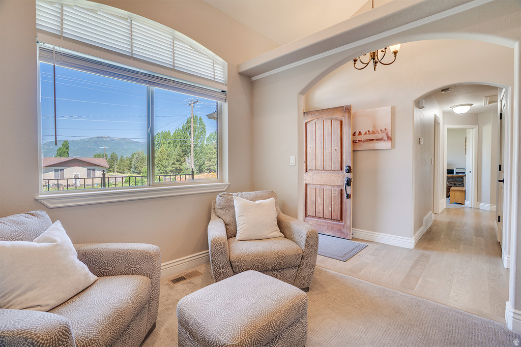 Spacious entrance featuring an arched doorway, wood-finish flooring, and a decorative light fixture