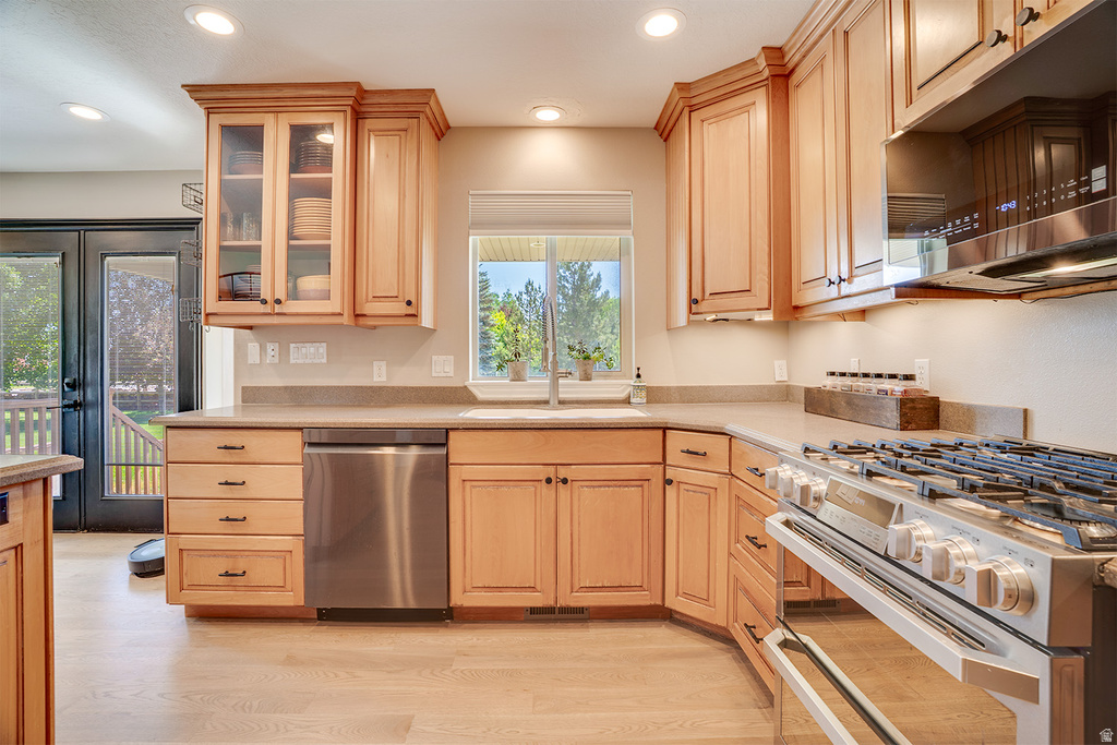 Kitchen featuring light wood cabinetry, a stainless steel gas range, and a coordinating stainless steel dishwasher