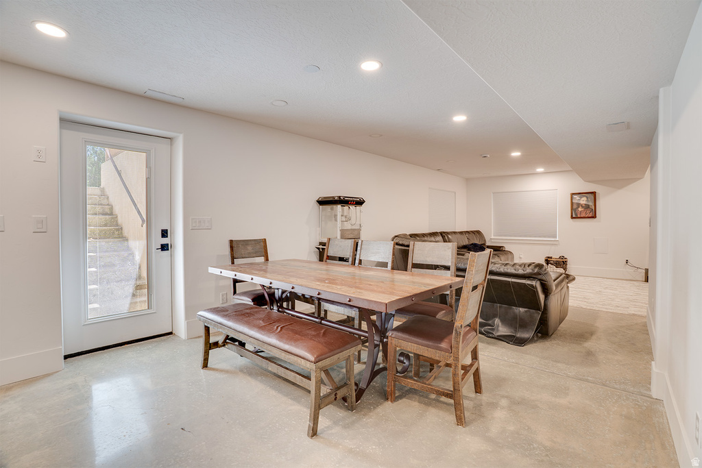 Spacious lower-level living area with recessed lighting, light-toned walls, and durable concrete flooring