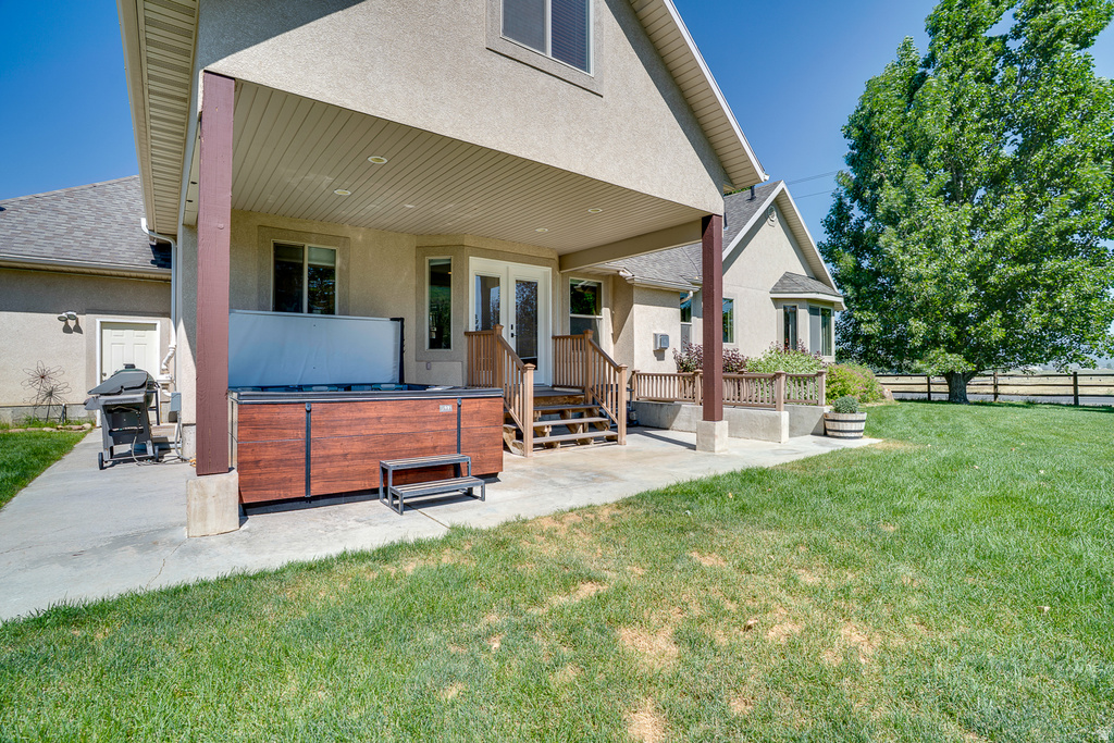 Covered patio featuring a built-in spa with wood-finish paneling, a concrete patio, and mature trees