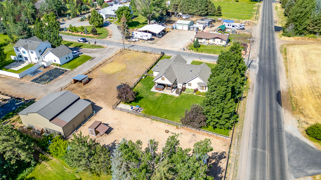 Expansive property featuring a single-family residence with a light-colored exterior and a dark roof, a large detached barn structure, and multiple fenced outdoor areas