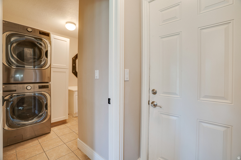 Dedicated laundry area featuring stacked appliances and tile flooring