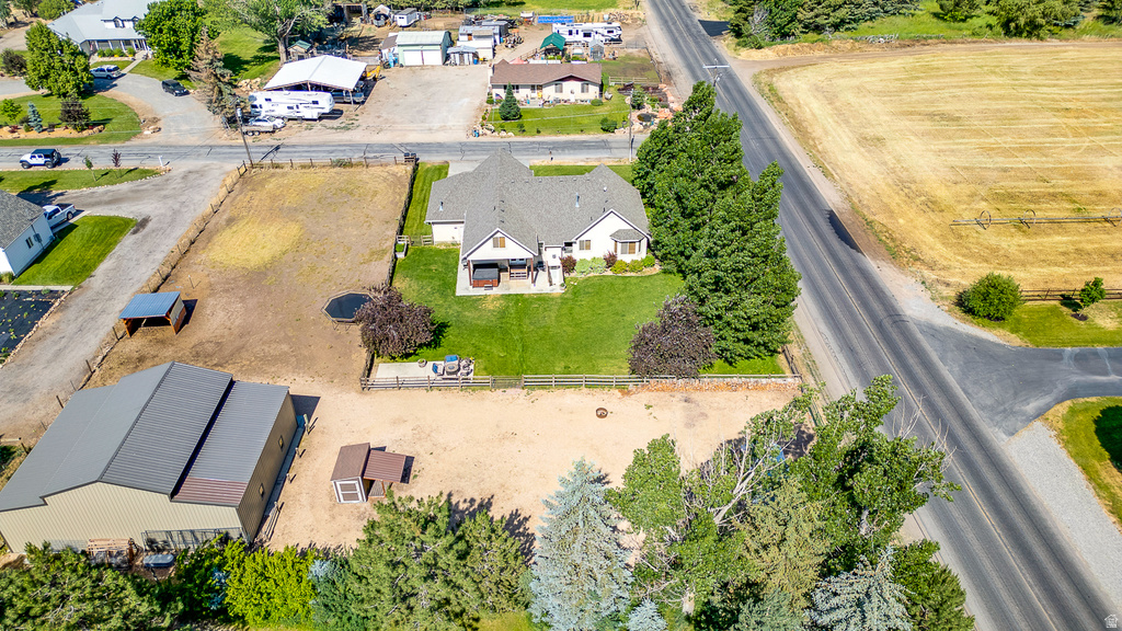 Expansive property featuring a residence with a covered porch, a separate large outbuilding with a metal roof, a fenced yard, and a substantial undeveloped lot