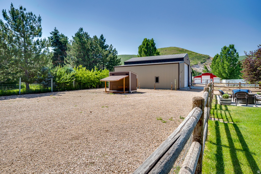 Extensive gravel lot with a large metal-sided building featuring a black roof and white garage doors