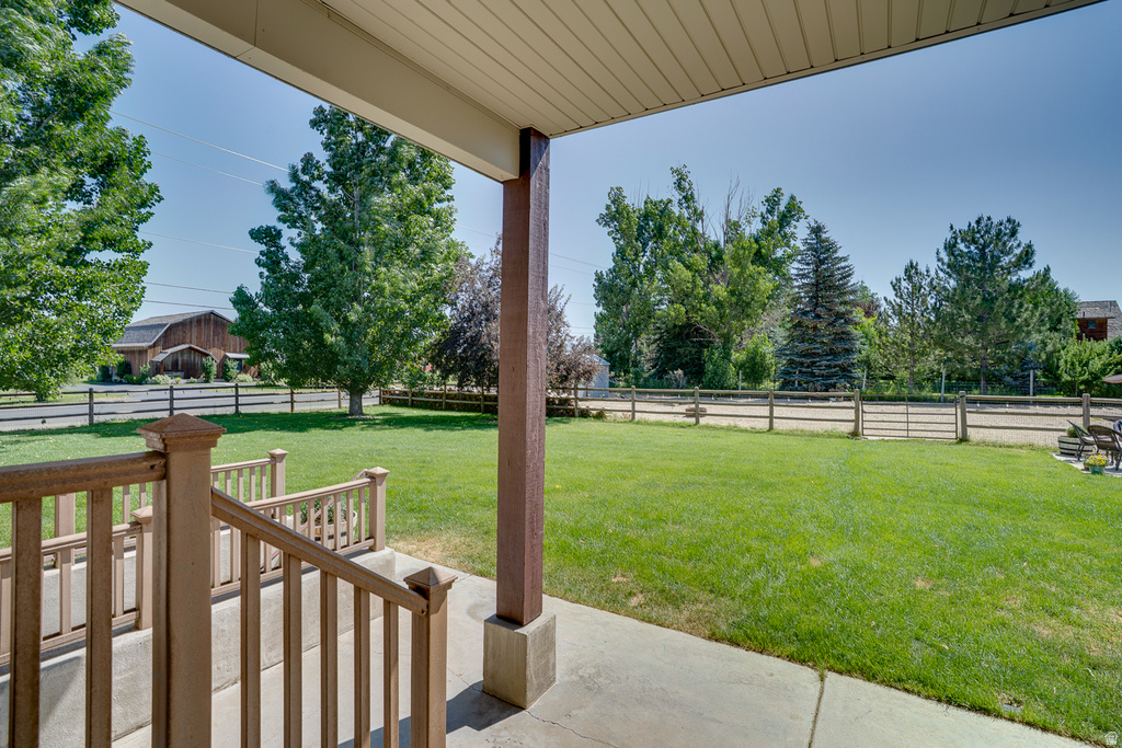 Covered concrete porch with wood-tone railings and a substantial support beam