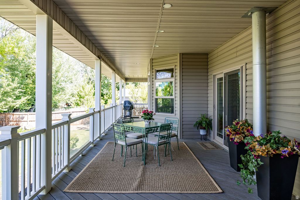 Expansive covered porch featuring a composite deck, white baluster railing, recessed lighting, and direct access through sliding glass doors