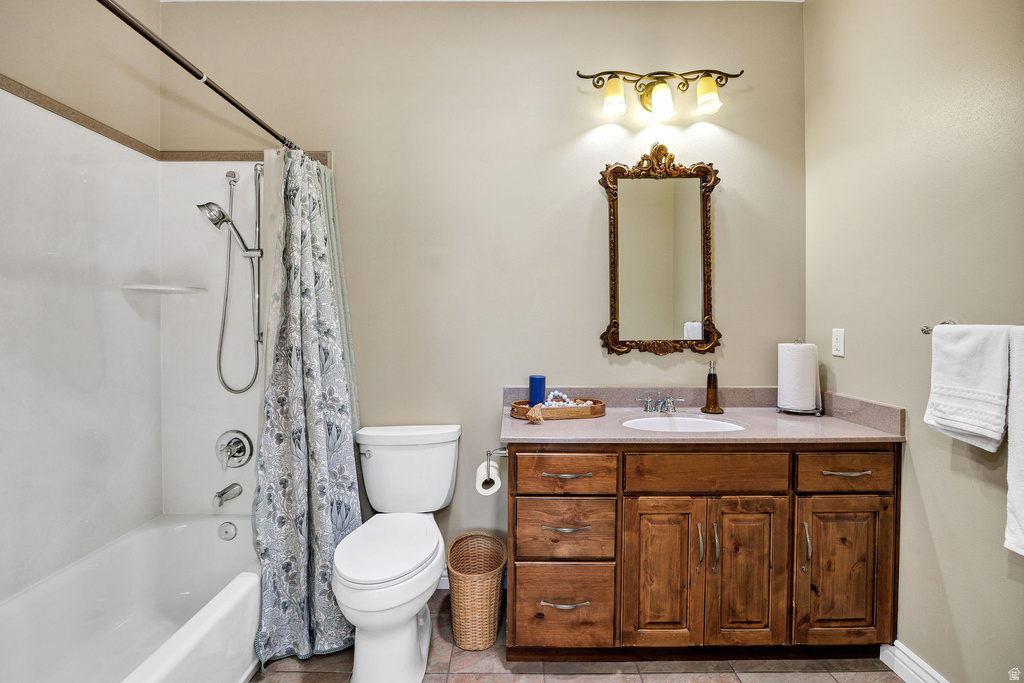 Full bathroom featuring a wood-finish vanity with a single basin sink, a framed mirror, a tub/shower combination, and a commode