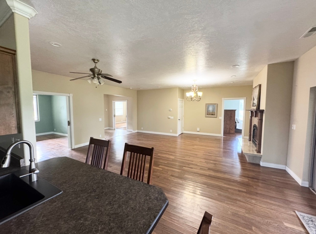Expansive main living area featuring wood-finish flooring, a fireplace with a mantel, and recessed lighting