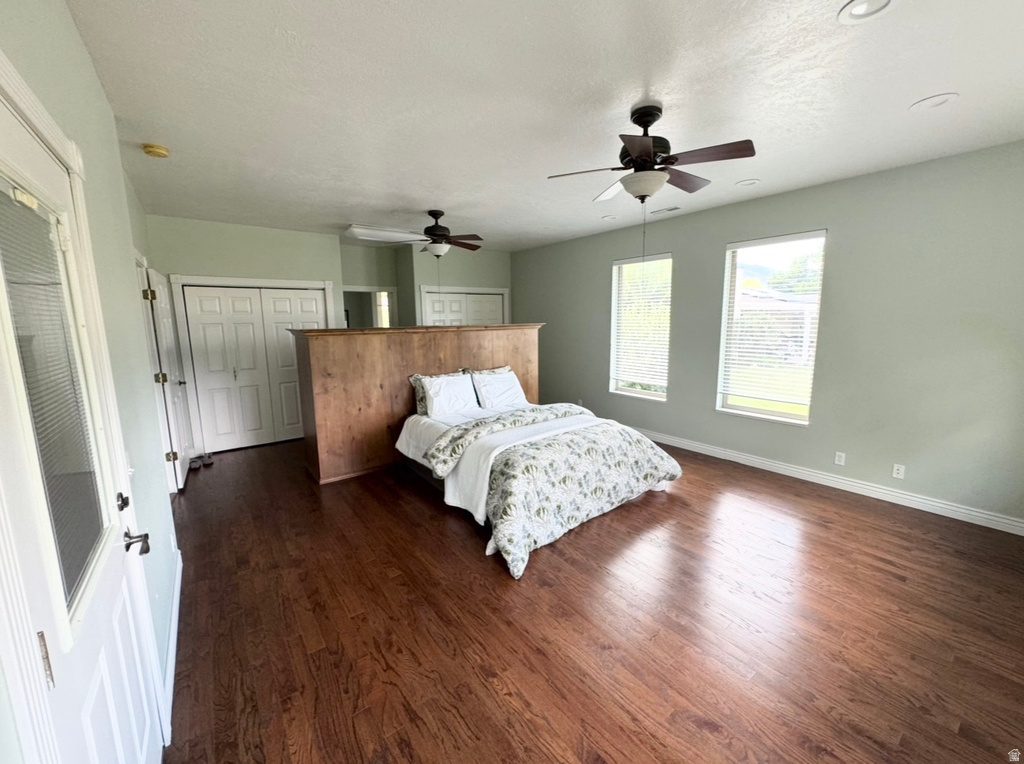 Spacious room featuring rich wood-finish flooring, multiple windows with blinds, and recessed lighting