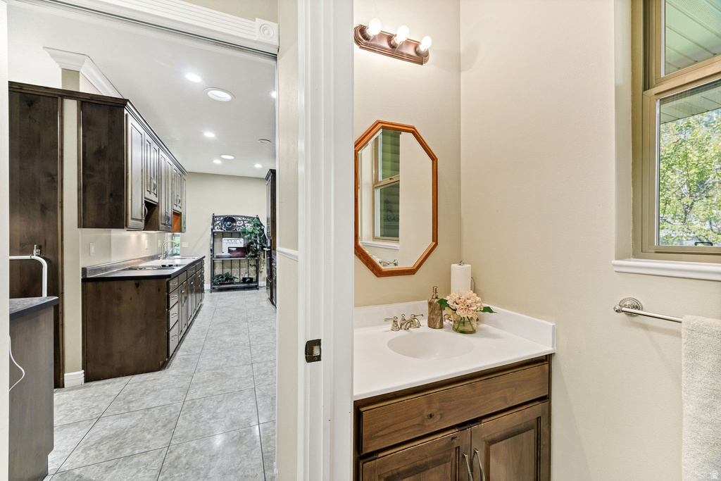 Bathroom vanity featuring a single basin sink, white countertop, wood-finish cabinet, and an octagonal mirror