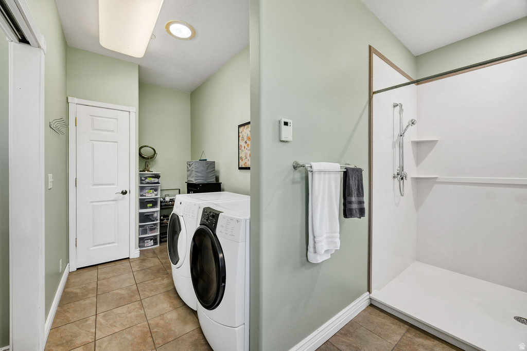 Combination laundry and shower room featuring tiled flooring, a white paneled door, a recessed ceiling light, and a white shower stall with built-in shelving