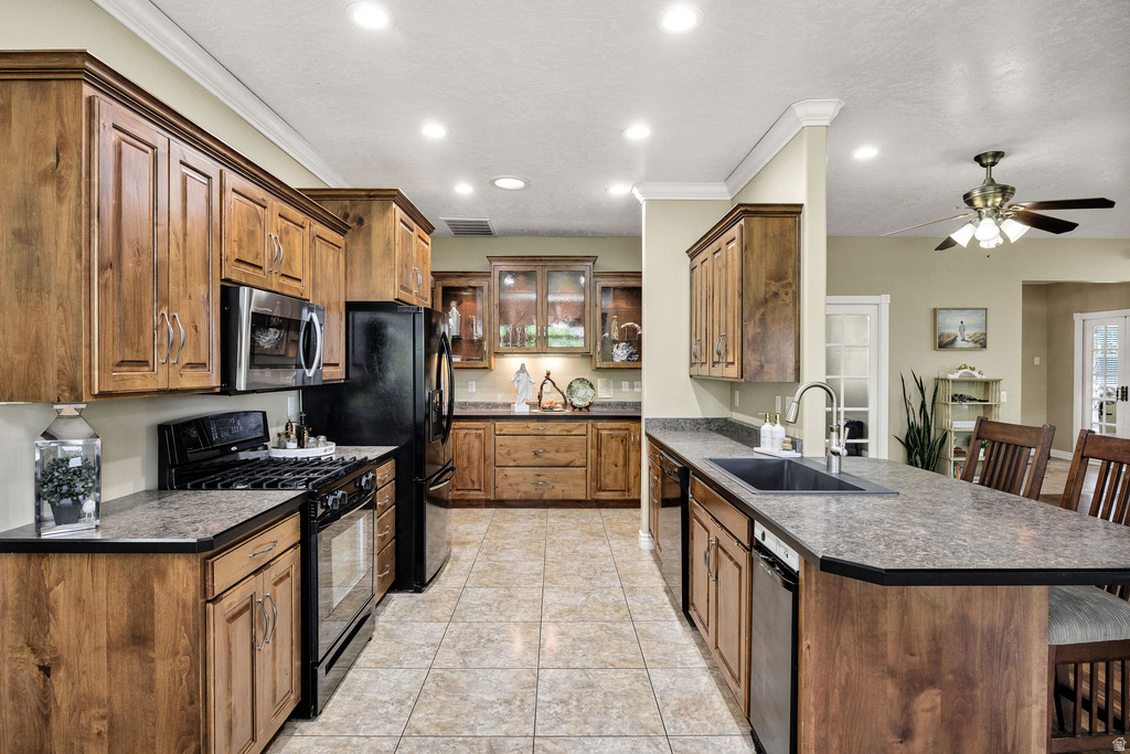 Kitchen featuring ample wood cabinetry, tile flooring, recessed lighting, and a kitchen island with a built-in sink and seating