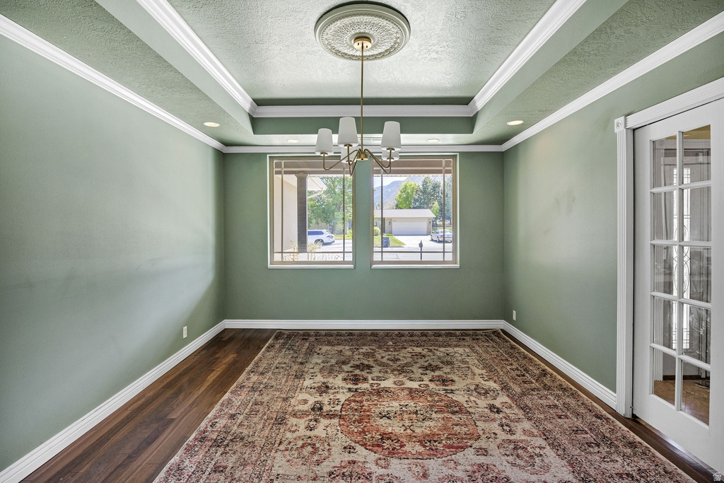 Formal room featuring a tray ceiling with recessed lighting and a central chandelier