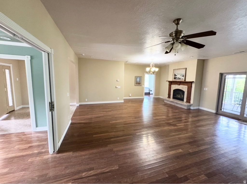 Spacious living area featuring wood-finish flooring, a ceiling fan, and a fireplace with a wood mantel