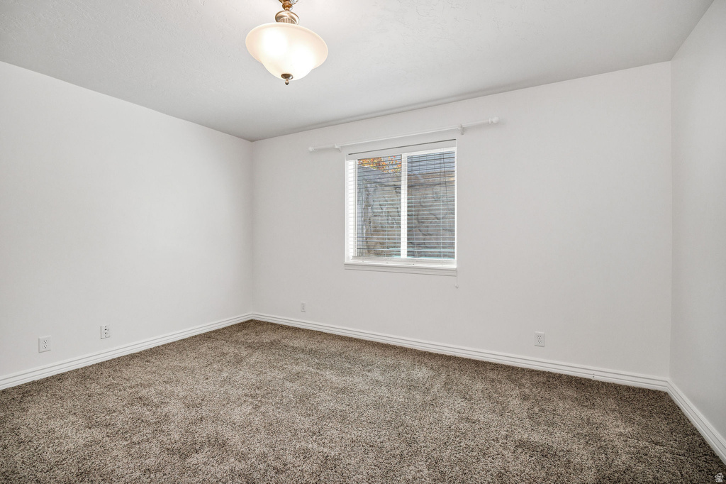 Bright interior space featuring neutral tone walls, a single window with blinds, and a flush mount ceiling light fixture