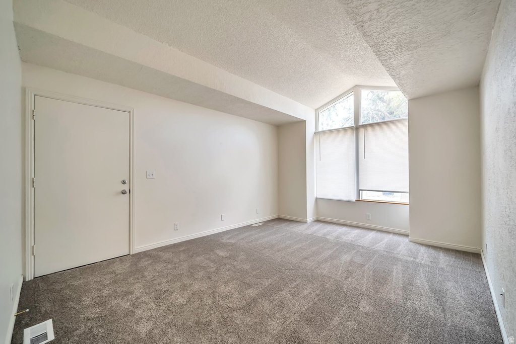 Room featuring grey patterned carpeting, white walls, and a textured ceiling