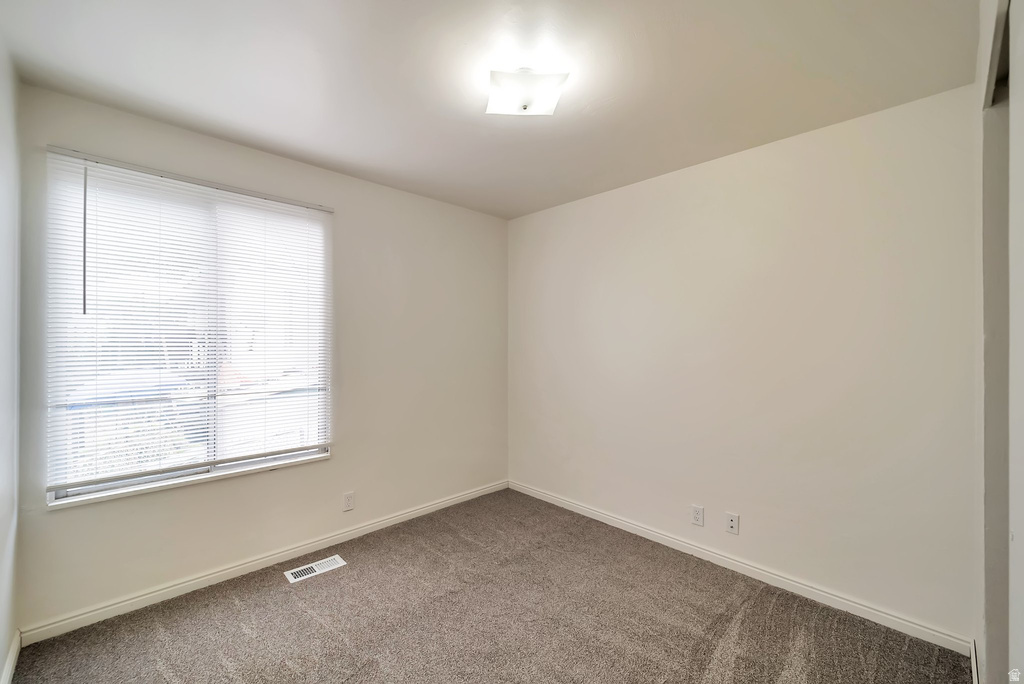 Interior room featuring neutral wall paint, carpet flooring, a window with blinds, and a ceiling-mounted light fixture