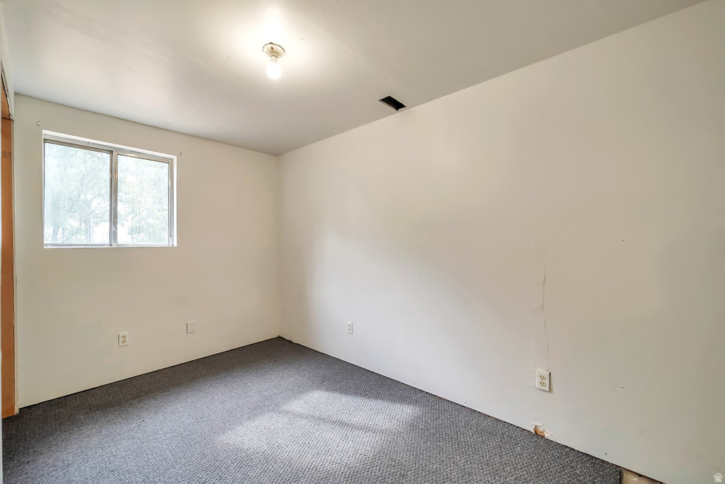 Room with white walls and dark gray carpet flooring