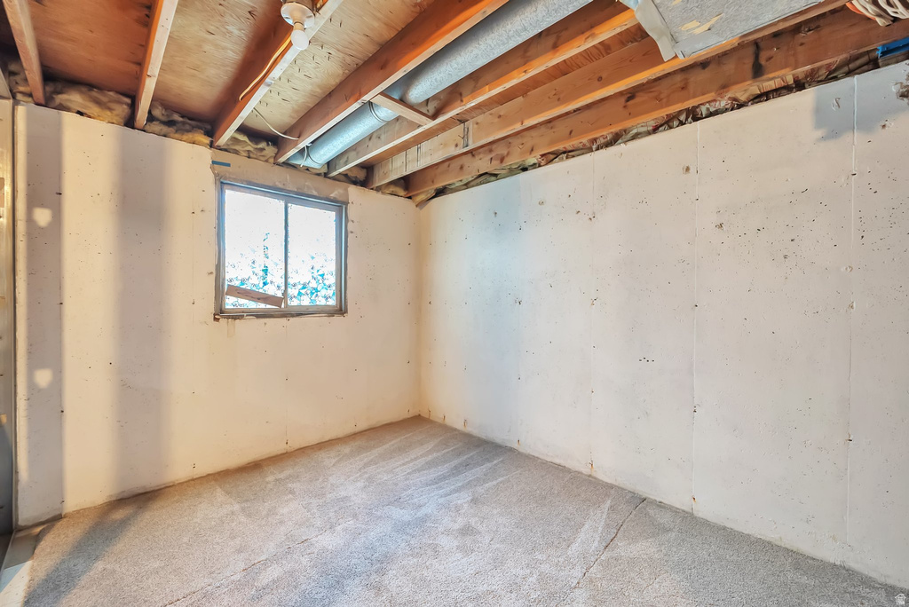 Carpeted floor with exposed ceiling joists and a functional window
