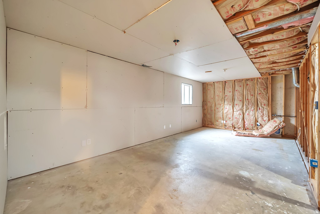 Unfinished basement space featuring a concrete floor, partial drywall installation, and exposed framing with insulation