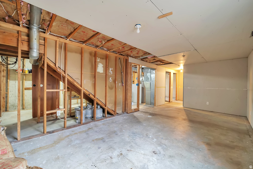 Unfinished basement space with exposed wooden framing, concrete flooring, and partial drywall installation