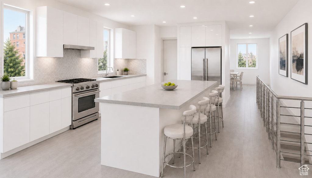 Sleek kitchen featuring white flat-panel cabinetry, light-toned countertops, and a full suite of stainless steel appliances