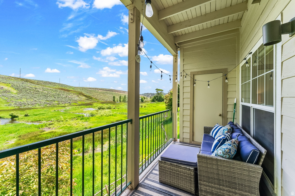 Covered balcony featuring a black metal railing and expansive green landscape