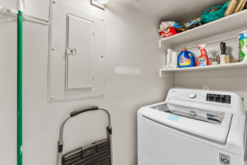 Dedicated laundry space featuring a built-in top-load washing machine and white floating shelves for storage