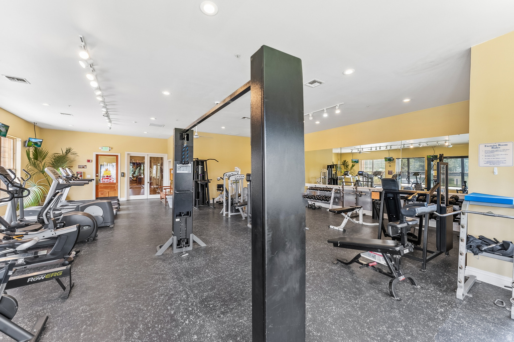 Fitness center featuring cardio and weight training equipment, mirrored wall, recessed lighting, and rubber flooring