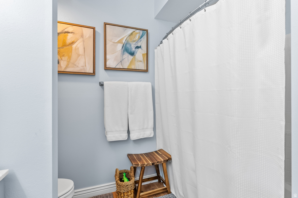 Bathroom featuring light blue walls, wood-finish flooring, and a white shower curtain with a waffle texture