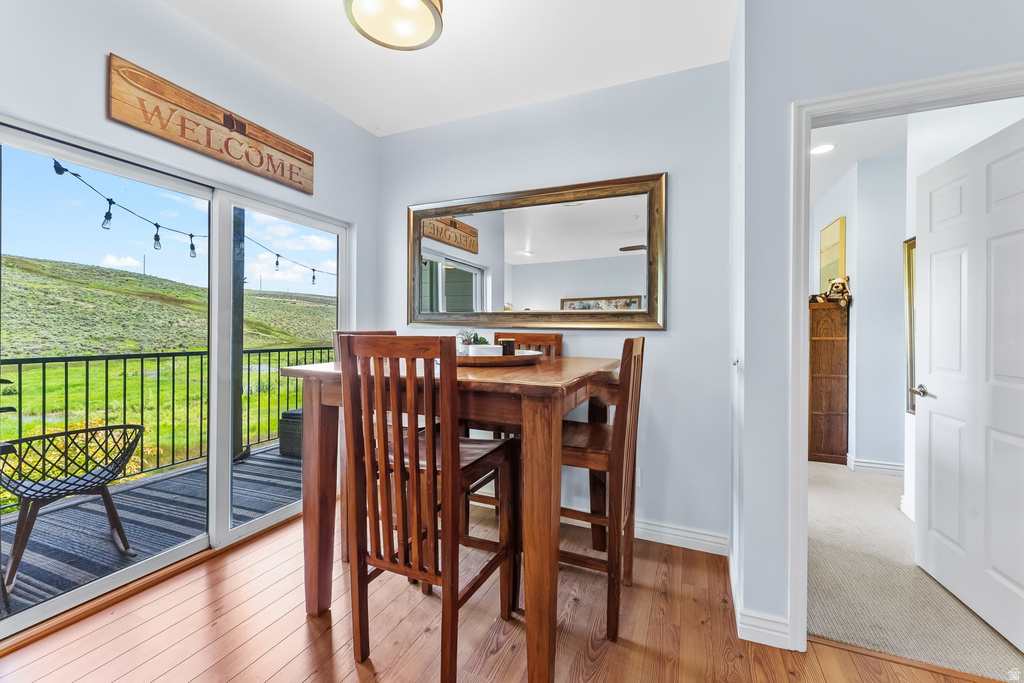 Sliding glass doors opening to a private balcony with black metal railing, offering expansive views of a natural green hillside