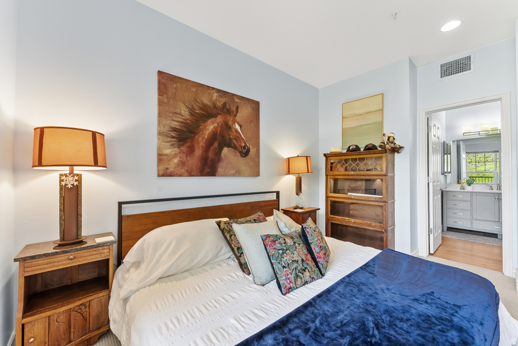 Carpeted bedroom with light blue wall paint and a wood-finish headboard