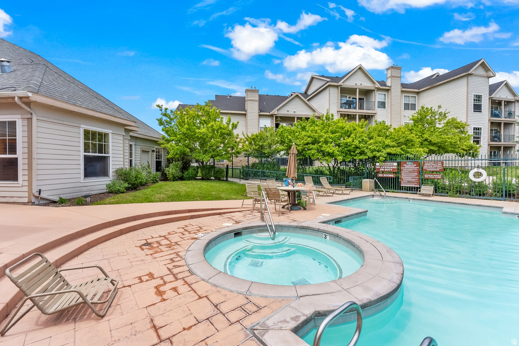 Outdoor amenity space featuring a swimming pool, integrated spa, and brick paver deck