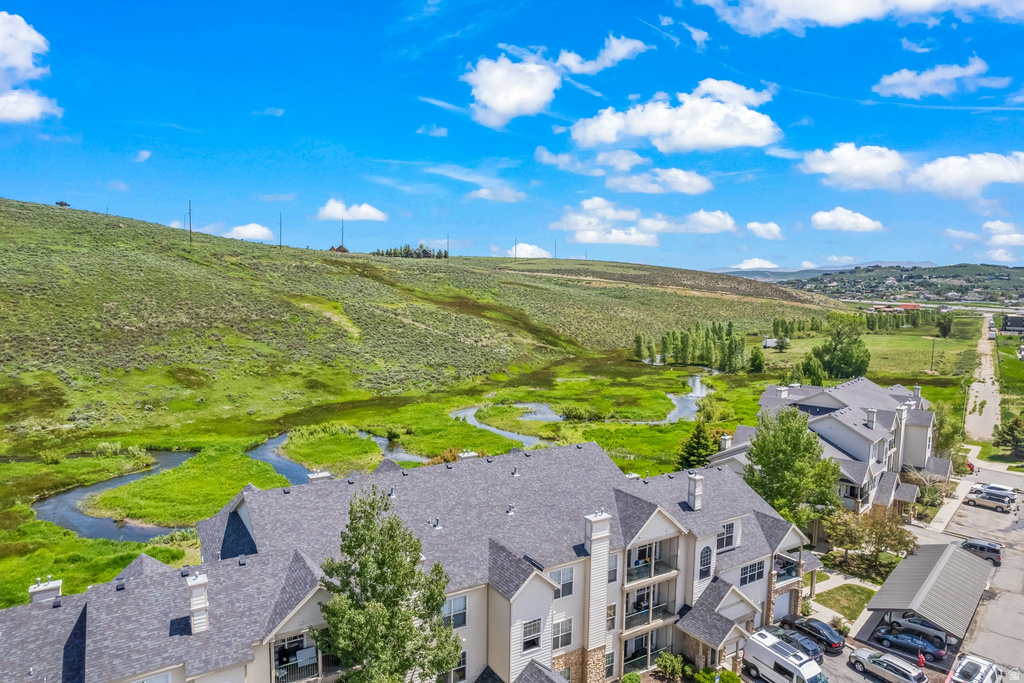 Multi-story residential buildings featuring gabled roofs and balconies overlooking a winding stream and natural green landscape