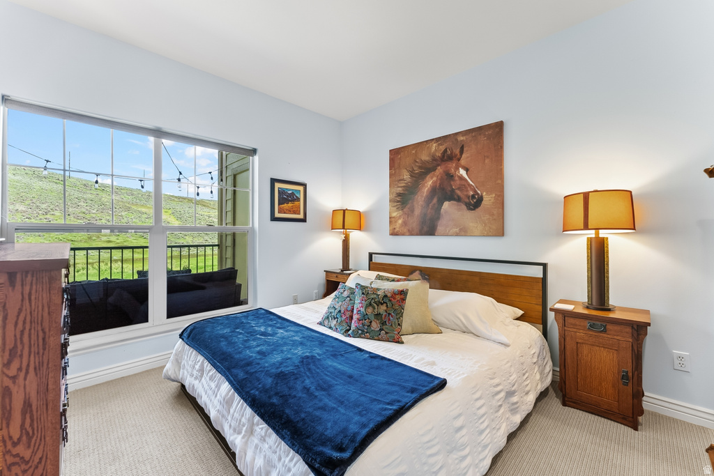 Bedroom featuring a large window, light-colored carpeting, and light blue walls