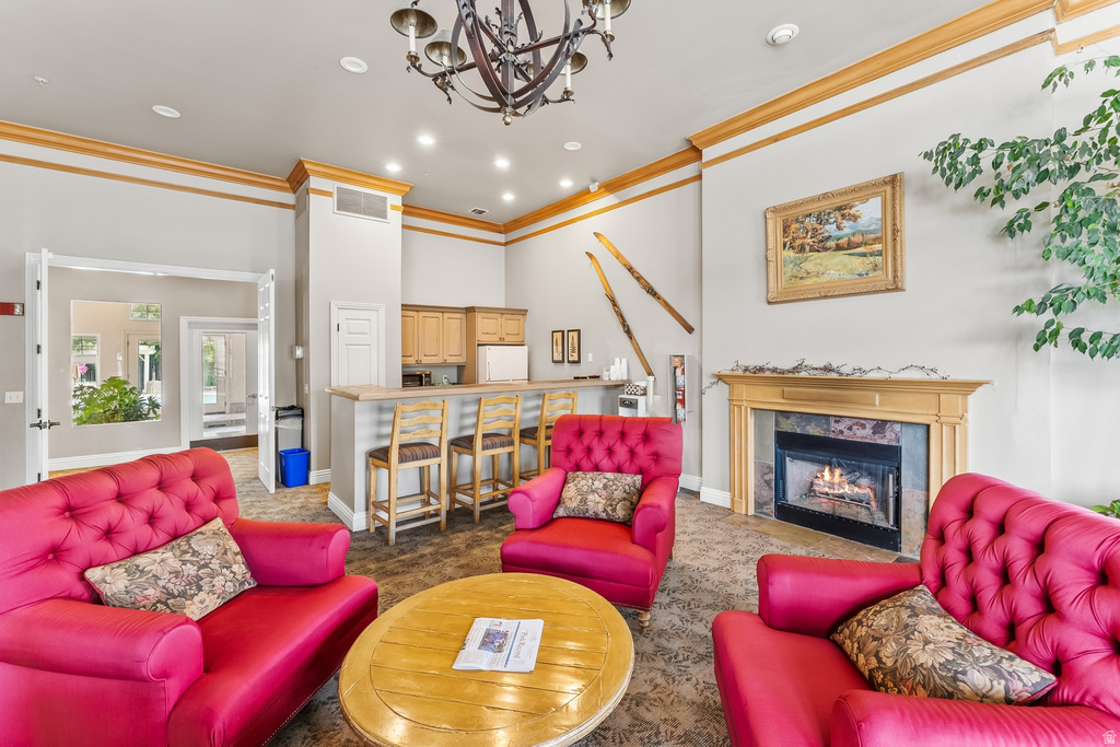 Spacious common area featuring a built-in fireplace with stone surround, a full-service bar with light wood cabinetry, and recessed lighting throughout