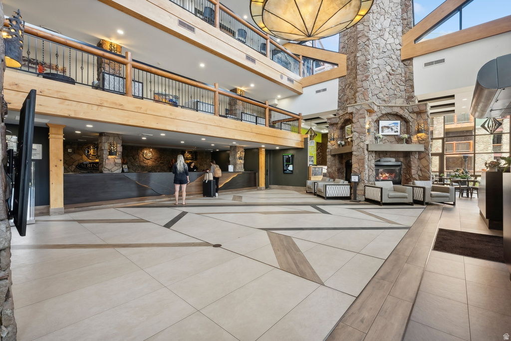 Two-story atrium featuring a stone fireplace, wood-finish flooring with geometric patterns, and upper-level balconies with wrought iron railings