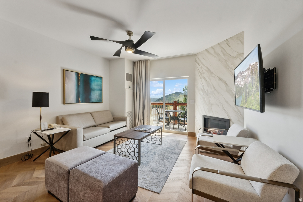 Living area featuring a floor-to-ceiling fireplace with a stone-finish surround, herringbone wood-finish flooring, and a sliding glass door opening to a balcony