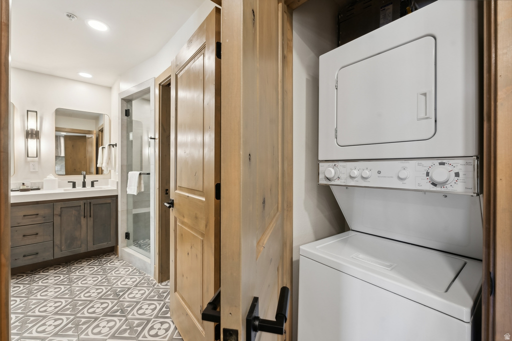 Bathroom featuring a patterned tile floor, a single vanity with a white countertop and gray cabinetry, a rectangular mirror, and wall-mounted sconces
