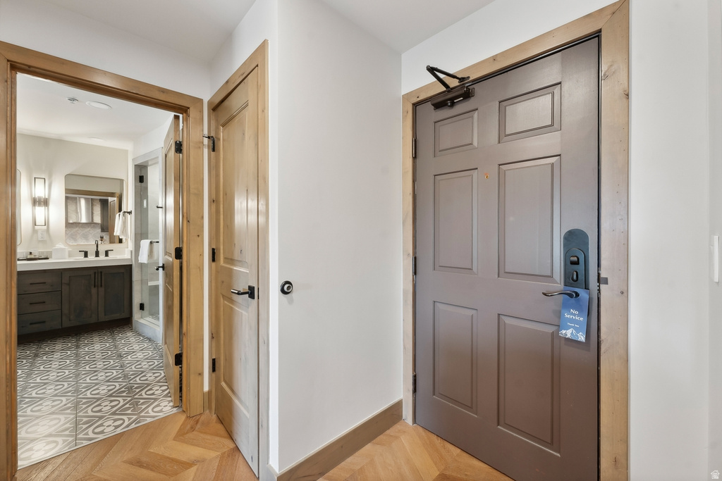 Herringbone wood-finish flooring extending into the hallway, featuring a solid panel door with dark hardware