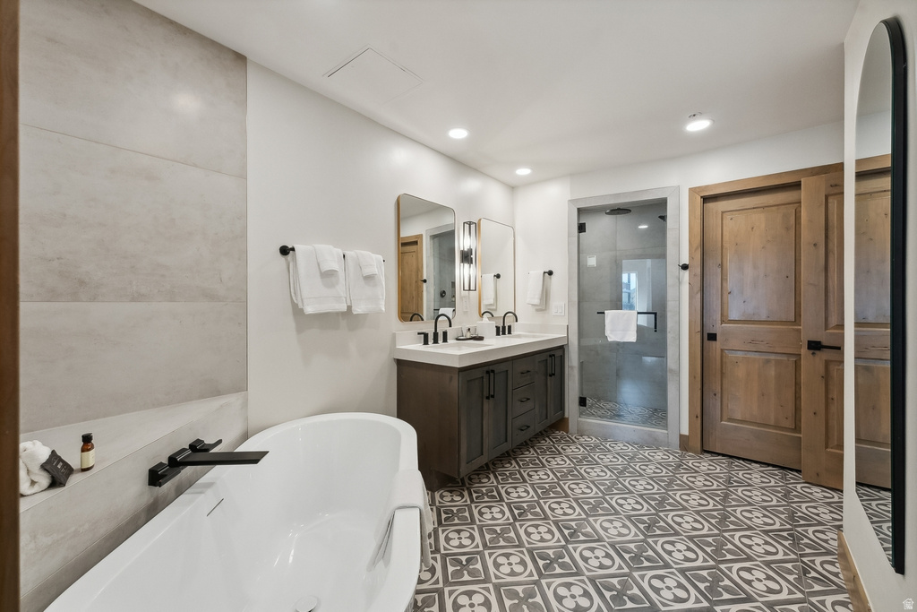 Contemporary bathroom featuring a freestanding soaking tub with a matte black faucet, a dual vanity with a white countertop, a walk-in shower with a glass enclosure, and patterned floor tiling
