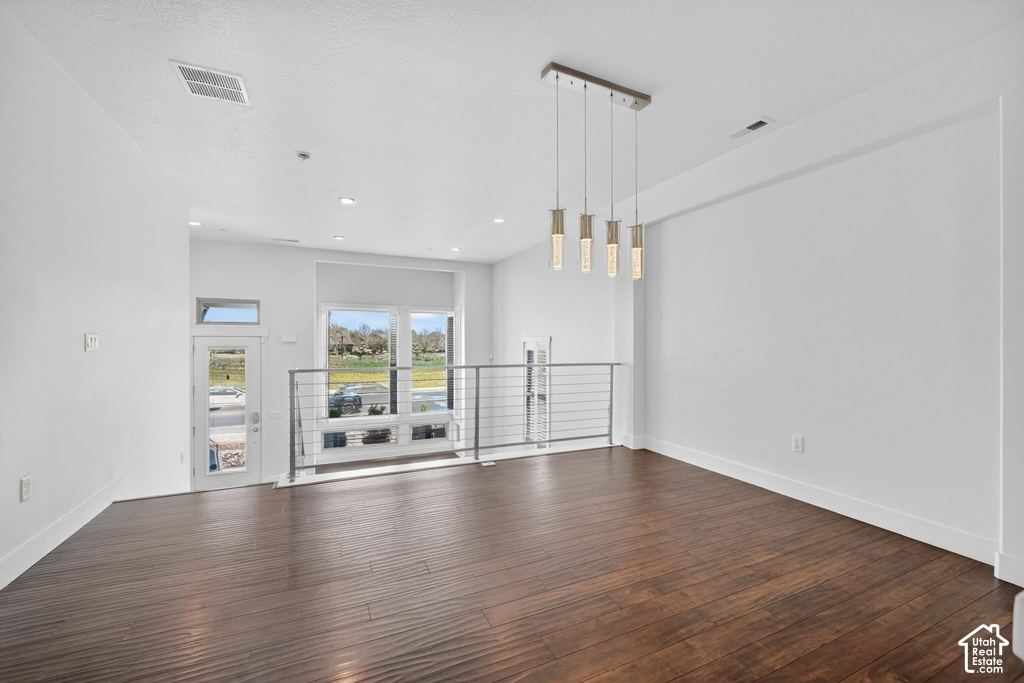 Open-concept interior featuring rich wood-finish flooring, a modern linear pendant light fixture, and recessed lighting